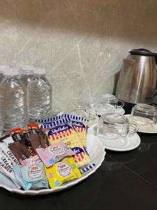 un plato de dulces en una mesa con vasos y botellas de agua en P3k suites barkada family room, en Manila