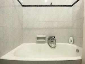 Una bañera blanca en un baño con azulejos blancos. en La casa di Palma, en Pachino