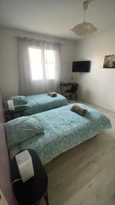 a bedroom with two beds and a table and window at Ophidia in Foix