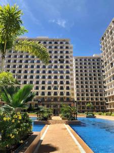a large building with palm trees and a swimming pool at Affordable Staycation near Airport and beach in Suba