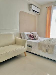 a bedroom with a bed and a couch and a window at Affordable Staycation near Airport and beach in Suba