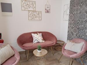 ein Wohnzimmer mit 2 rosa Stühlen und einem Tisch in der Unterkunft OLTREMARE holiday home in Catania