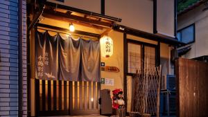 Una donna in piedi di fronte a un palazzo con una tenda di Kyonoyado Senkakubettei a Kyoto