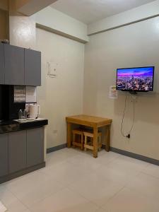 Una cocina con una mesa y un televisor en la pared. en P3k suites barkada family room, en Manila