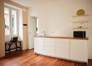 a kitchen with white cabinets and a microwave at Appartamento BACCO in Feriolo