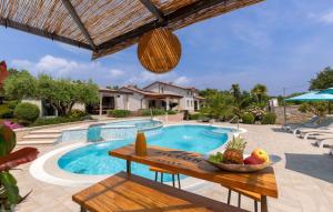 a swimming pool with a table and a bowl of fruit next to it at Family villa Filton with wellness in Vizinada in Vranje Selo