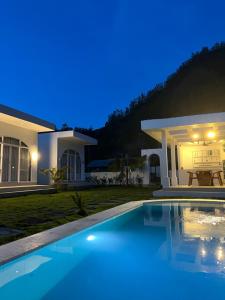 a villa with a swimming pool in front of a house at Montana villas by volcano garden in Kubupenlokan