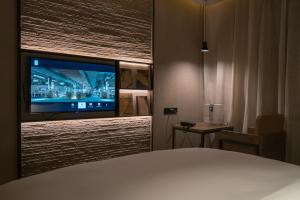 a room with a bed and a tv on a wall at Jiayuguan Tuzhu Hotel in Jiayuguan