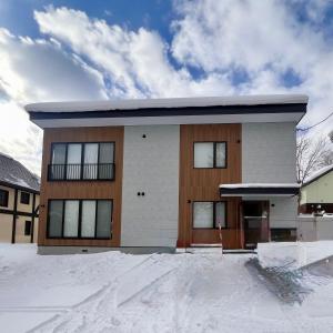 a house with snow in front of it at Snow Monkey Loft in Kutchan