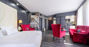 a bedroom with a bed and two red chairs at PLAZA Premium Schwerin Sure Hotel Collection by Best Western in Schwerin