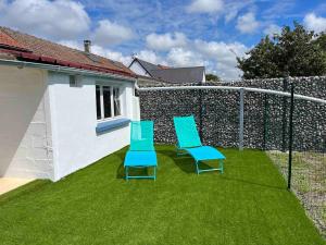 two blue chairs sitting on a lawn next to a fence at La p'tite camargue in Le Crotoy