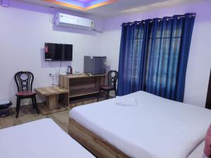 a bedroom with two beds and a desk and a tv at Pavilion City Hotel in Nowgong
