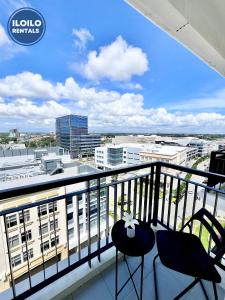 a balcony with two chairs and a view of a city at Experience Elegance at Chambre Honore in Iloilo City