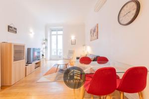 a living room with a table and chairs and a clock on the wall at Le Viallet - 3 chambres centre ville - Clim-proche gare in Grenoble