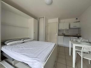 Un dormitorio con una cama y una mesa y una cocina. en Appt 1 pièce CHATELAILLON PLAGE - CL090-021, en Châtelaillon-Plage