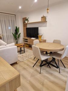 a living room with a table and chairs and a tv at La Flor del Cantábrico in Ribadeo