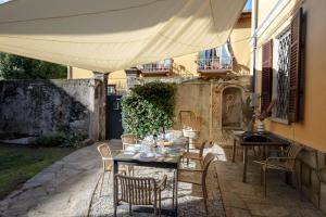 a patio with a table and chairs under an umbrella at Casa Felice - Villa con Giardino in Centro in Verbania