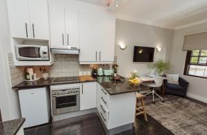 a kitchen with white cabinets and a table with a microwave at Studio in Central Stellenbosch in Stellenbosch