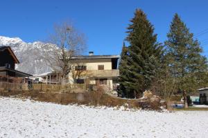 a house with trees in front of a snow covered mountain at Haus Frei-Zambra in Vandans