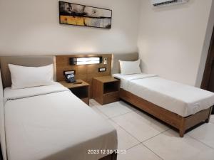a hotel room with two beds and a phone at Hotel Occazia Lubumbashi in Lubumbashi