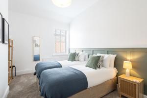 two beds in a hotel room with two lamps at Glasswing Stays Newbiggin Beach House in Newbiggin-by-the-Sea