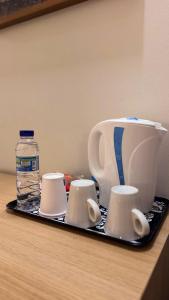 a tea kettle and cups on a tray with a bottle of water at Sea Garden Peniche in Peniche
