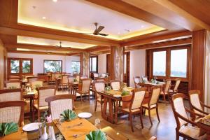 Chandys Windy Woods Munnar في مونار: مطعم بطاولات وكراسي خشبية ونوافذ