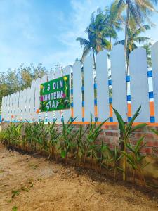 a white fence with a sign on it with palm trees at PS Din Kontenastay in Kota Bharu +11 photos