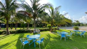 a group of tables and chairs in a park with palm trees at Coconutpalm Home in Hengchun South Gate
