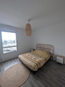 a bed in a room with a window and a rug at Le Panoramique in Hennebont