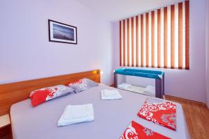 1 dormitorio con 1 cama con almohadas rojas y blancas en Apartments Dimitrovi, en Pomorie
