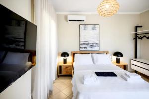 a bedroom with two beds and a chandelier at ML Houses Lefkada in Tsoukalades