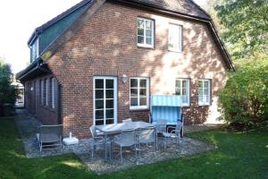 une table et des chaises devant une maison en briques dans l'établissement Ferienhaus Adebar 1, à Oevenum