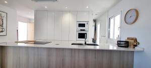 Una cocina blanca con encimera y un reloj en la pared. en Villa Escara, en San Javier 27 fotos más