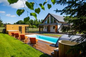 a house with a swimming pool with chairs around it at Masuria Rosa in Regiel