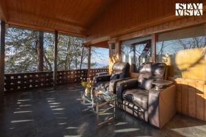 una veranda schermata con 2 sedie in pelle e un tavolo di Chalet Rushli - Free Breakfast with Valley View at Mussoorie by StayVista a Kanatal