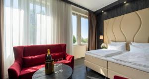 a bedroom with a bed and a red chair and a bottle of wine at PLAZA Premium Schwerin in Schwerin +109 photos