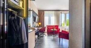 a kitchen with red chairs and a living room at PLAZA Premium Schwerin in Schwerin