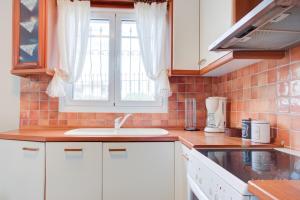 a kitchen with white cabinets and a sink and a window at Azure Bay Villa by RentalsPro - Neos Marmaras Halkidiki in Paradisos