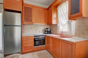 a kitchen with wooden cabinets and a stainless steel refrigerator at Azure Bay Villa by RentalsPro - Neos Marmaras Halkidiki in Paradisos