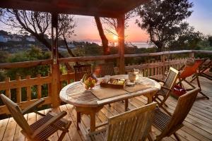 a wooden table and chairs on a deck with the sunset at Camping Au Paradis des Campeurs Premium in Roquebrune-sur-Argens