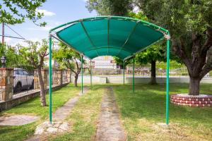 a green canopy in a park with trees at Azure Bay Villa by RentalsPro - Neos Marmaras Halkidiki in Paradisos