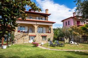 a large stone house with a yard with chairs at Azure Bay Villa by RentalsPro - Neos Marmaras Halkidiki in Paradisos