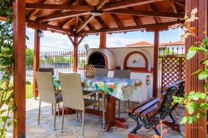 a patio with a table and chairs under a wooden pergola at Azure Bay Villa by RentalsPro - Neos Marmaras Halkidiki in Paradisos