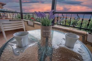 a table with two cups and a vase with purple flowers at Azure Bay Villa by RentalsPro - Neos Marmaras Halkidiki in Paradisos