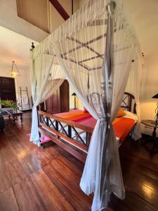 a bedroom with a bed with a mosquito net at The Garden House Galle - Garden View Room in Galle