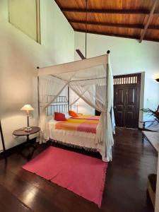 a bedroom with a canopy bed and a red rug at The Garden House Galle - Garden View Room in Galle