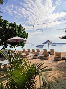 a group of chairs and umbrellas on a beach at Bale Sampan Boutique Bungalows in Gili Trawangan