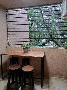 a table and two stools in front of a window at Allende Suite Villa Allende in Villa Allende