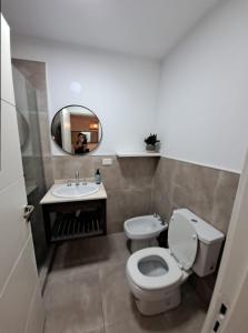 a bathroom with a toilet and a sink and a mirror at Allende Suite Villa Allende in Villa Allende